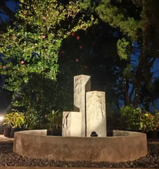 A lit stone water feature at dusk in the Chairman's Bungalow garden.
