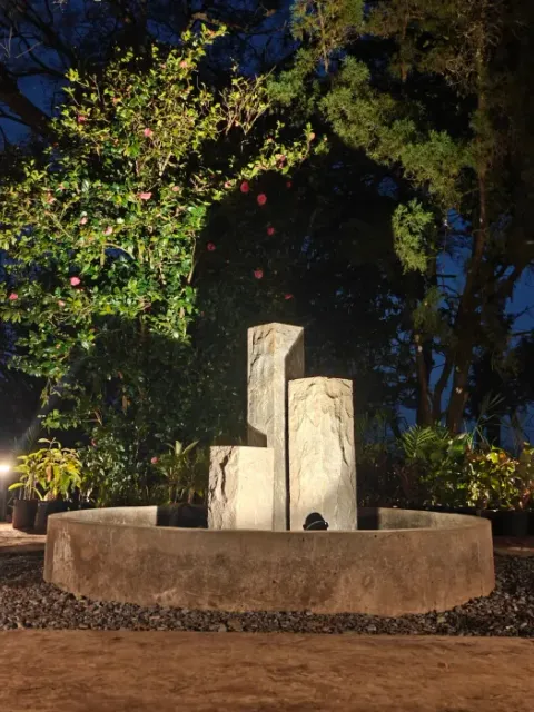 A lit stone water feature at dusk in the Chairman’s Bungalow garden.