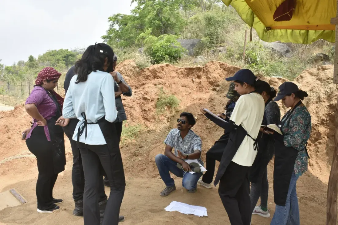 Students and practitioners gathered around a facilitator at a hands-on landscape design field workshop.